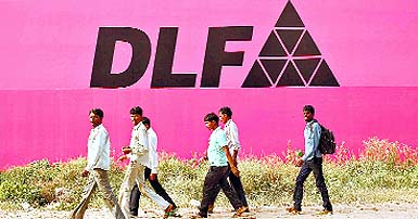 Workers walk past a billboard of DLF in Gurgaon on Tuesday. The company will be forced to sell assets, even unfinished projects, to meet debt obligations, say bankers, after it was banned from the capital markets for three years  SEBIs harshest penalty ever. 