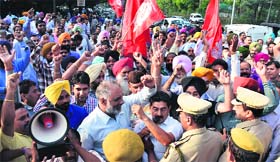 Policemen try to pacify protesting members of the Coordination Committee of UT and MC employees near the cricket stadium in Sector 16, Chandigarh, on Tuesday.
