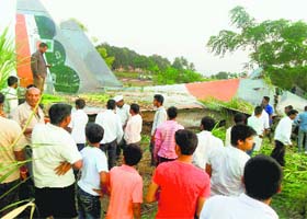 People gather near a Sukhoi SU-30MKI fighter jet that crashed at village Theoor near Pune on Tuesday