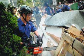 A policeman uses a chainsaw to remove barricades in Admiralty district of Hong Kong on Tuesday