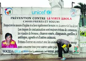 A man hangs a banner that lists about measures to avoid the Ebola virus