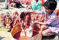 A girl pours colour on to an idol of Lord Ganesha for the upcoming Diwali festival, on the outskirts of Amritsar on Thursday