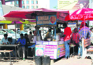 People have food at a roadside eatery in Amritsar on Saturday unmindful of the health hazards.