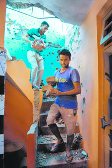 People clear debris from their damaged home following cross-border firing at Arnia village, 30 km from Jammu.