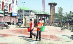 Students of Gassiyar Shaheen Public High School spray disinfectant at Lal Chowk in Srinagar. Tribune Photo: Yawar Kabli