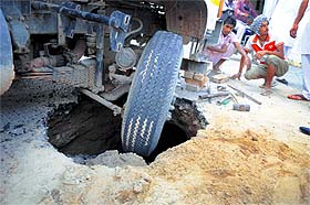 A truck gets stuck after a road caves in at Vishal Nagar on Saturday. It was recarpeted four months ago. 