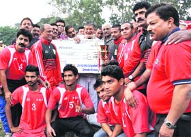 Chief Minister Harish Rawat and Sports Minister Dinesh Aggrawal give the winner trophy to the FCI Delhi team during the closing ceremony of the Narendra Kharola Memorial Football Tournament at Pavilion Ground in Dehradun on Sunday