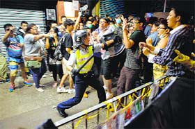 A cop advances towards protesters in Mong Kok