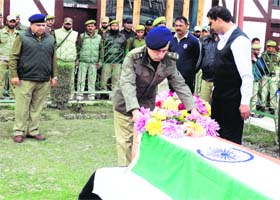 A police officer pays tributes to the slain constable at the District Police Lines in Srinagar on Monday