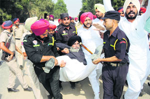 Policemen detain Inderjit Singh Zira, former Congress MLA, outside the residence of Chief Minister Parkash Singh  Badal at Badal village in Lambi on Monday. 