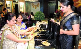 An employee shows gold jewellery to prospective customers at a store in Amritsar on Tuesday.