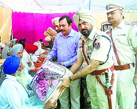 Police officials distribute blankets among family members of martyrs at Khanna. 