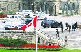 Armed police officers approach a building on Parliament Hill following a shooting incident in Ottawa on Wednesday