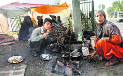 Members of a family displaced by the floods have tea near their tent on the outskirts of Srinagar. A file photograph