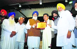Parkash Singh Badal, Chief Minister, honours an industrialist at Vishwakarma Day celebrations in Ludhiana on Friday.