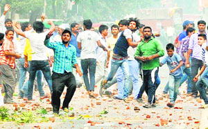 Youths throw stones during a clash in the Trilokpuri area on Saturday. 