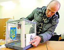 An election commission worker adjusts a number on a ballot box at a polling station in Kiev on Saturday