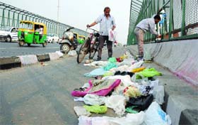 ASWACHH ACT: Polythene bags lay scattered at ITO Yamuna Bridge as a man throws puja materials into the river in New Delhi on Sunday