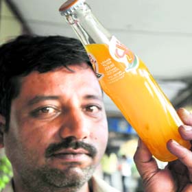 A customer shows a soft drink bottle that allegedly contained  algae in Amritsar on Monday