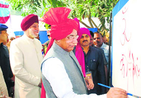 Governor Kaptan Singh Solanki writes his name during the inaugural function of Ratnawali at Kurukshetra University on Monday.