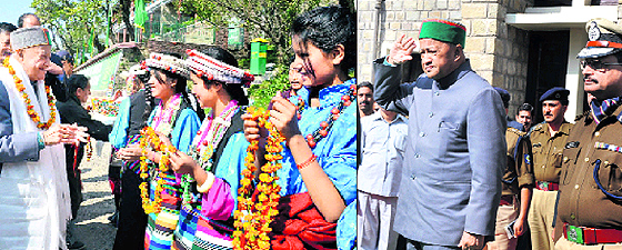 Chief Minister Virbhadra Singh being welcomed by Tibetan children on his arrival at TCV in McLeodganj; and (right) the CM takes the salute after inaugurating a women police station in Dharamsala on Monday.