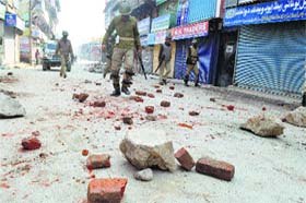 Securitymen walk through a Srinagar street after a protest against the government for imposing restrictions following a shutdown called by separatists