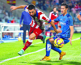 Atletico Madrids Arda Turan and Getafes Sergio Escudero vie for the ball during their La Liga match in Getafe on Sunday. 