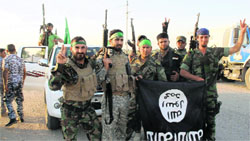 Shia fighters pose with a black flag belonging to the Islamic State, which they pulled down after capturing the town of Jurf al-Sakhar from IS militants, south of Baghdad on Sunday. Reuters