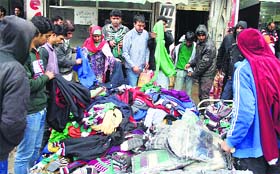 People buy warm cloths from a vendor ahead of the winter season in Srinagar on Tuesday.