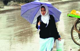 A student walks with an umbrella as it rains in south Kashmirs Anantnag district on Tuesday.