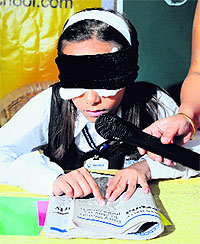 A blindfolded Jiya Phutela reads a newspaper during a press meet at Sector 27 in Chandigarh on Wednesday.