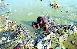 A man looks for coins and other items of value in the polluted waters of Ganga in Allahabad