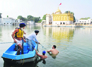 Divers jump in Durgiana Temples pool to retrieve the body of Kanhaya, who drowned in it on Thursday morning. 