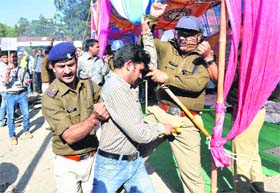 Policemen arrest diploma pharmasists during their protest at the Parade Ground in Dehradun on Thursday