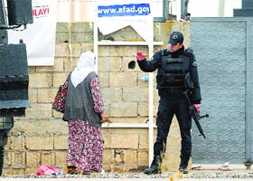 A Turkish policeman stops a Kurdish woman as she approaches the gate of a camp that hosts Peshmerga fighters in the border town of Suruc on Thursday