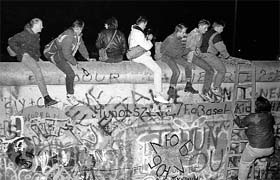West German citizens sit on top of the Berlin Wall near the Allied checkpoint Charlie after the opening of the East German border was announced in this picture taken on November 9, 1989. Germany will celebrate the 25th anniversary of the fall of the wall on November 9, 2014.
