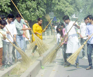 Students of ABVP and DUSU clean a roadside during the Campus Cleanliness Drive in North Delhi on Monday.