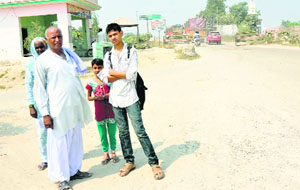 Passengers wait for a bus at Manglora village of Karnal on Monday.