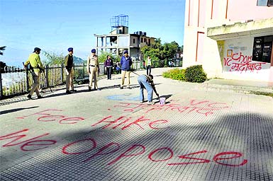 An employee whitewashes the slogans at the Arts Block in HP University in Shimla on Monday. 