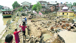 People walk past a breached river bank of the Jhelum near Lal Chowk area of Srinagar. A file Photo
