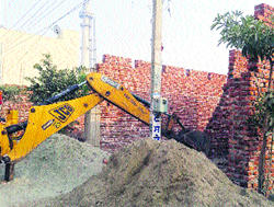 A JCB demolishes an illegal building in Jalandhar on Monday.