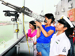 A naval officer helps a schoolgirl have a look at a gun on INS Sumitra at an exhibition organised as part of Navy Week celebrations in Kolkata on Tuesday
