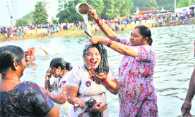 Devotees take a holy dip in a pond during the annual Jhiri fair at Kanachack village on the outskirts of Jammu on Thursday.