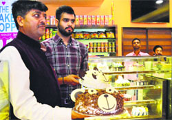 Owners of a bakery display a cake in Ludhiana.