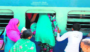 A passenger tries to enter a train through a window due to a heavy rush of pilgrims at the railway station in Haridwar on Thursday