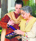 Congress president Sonia Gandhi and Gursharan Kaur, the wife of former PM Manmohan Singh, look at the award given to him by Japan, in New Delhi.