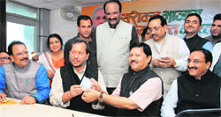 Shyam Jaju, in charge of the Uttarakhand BJP, gives party membership slip to state BJP president Teerath Singh Rawat at the party office in Dehradun on Saturday. Tribune photo: Vinod Pundir