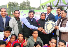 Chief guest Narayan Singh Rana presents the winning trophy to Himalayan Panchawati Sports Foundation team members who won the District Volleyball Championship in the womens category at Global Sports Academy in Dehradun on Saturday