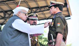 Governor Aziz Qureshi gives a medal to ADG Ram Singh Meena
