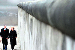 German Chancellor Angela Merkel (R) and Berlin Mayor Klaus Wowereit walk by a preserved segment of the Berlin Wall